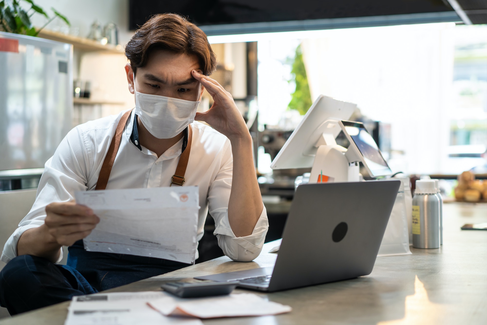 Asian café owner man look frustrated to bills and payment for business in restaurant shop.